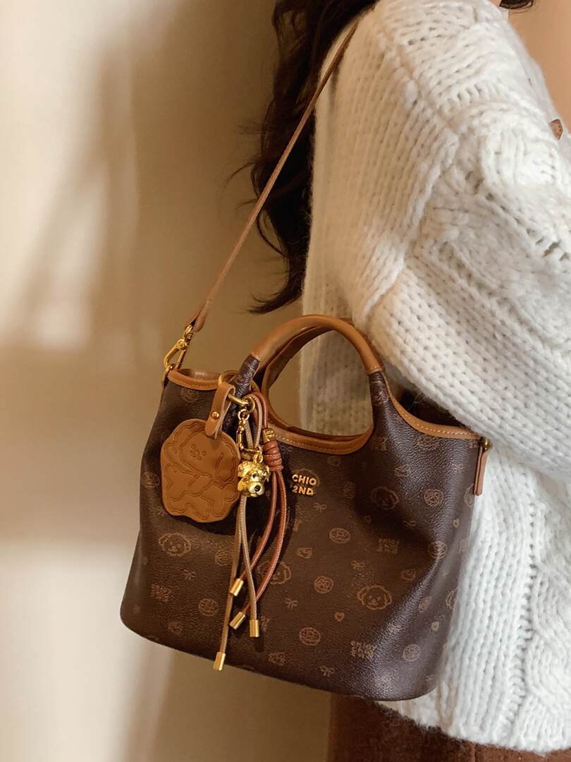Brown monogram handbag worn over a white knit sweater