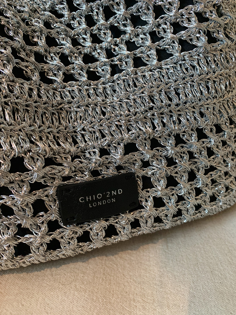 Close-up of a silver woven CHIO'2ND London handbag or clutch