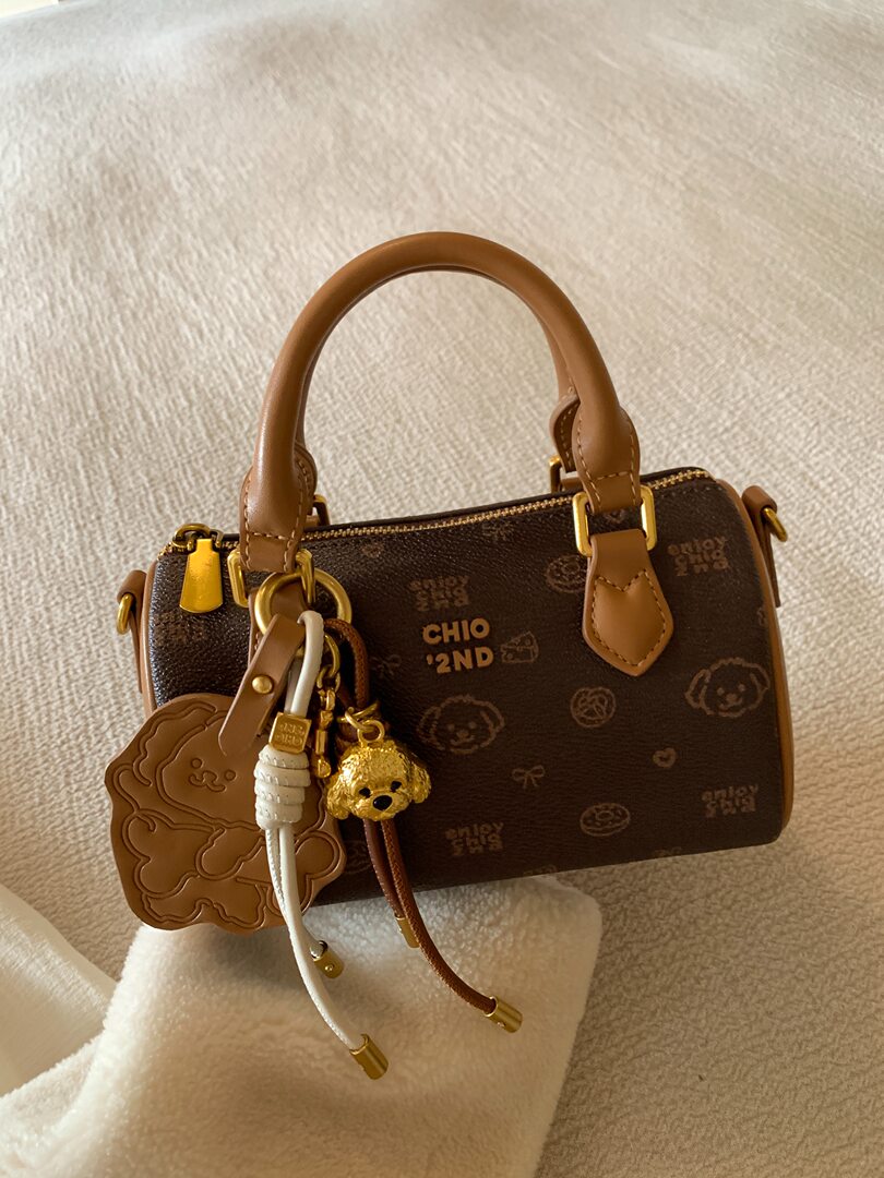 Brown mini handbag with tan handles and decorative keychain charms