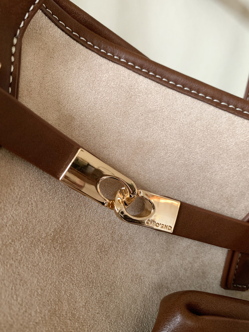 Close-up of a brown and beige leather handbag with a gold clasp
