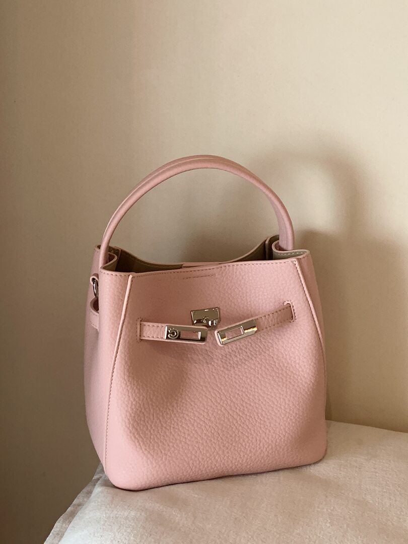 Pink leather handbag with top handle and silver hardware on a neutral background