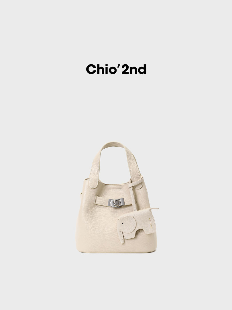 Cream textured mini handbag with a small elephant charm on a white background
