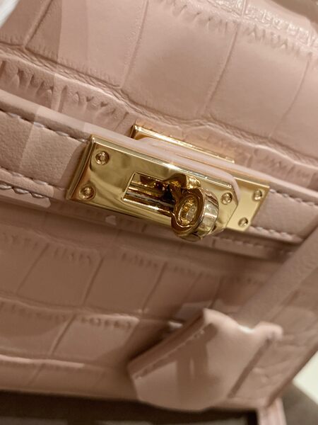 Close-up of a blush pink quilted handbag with a gold turn-lock clasp