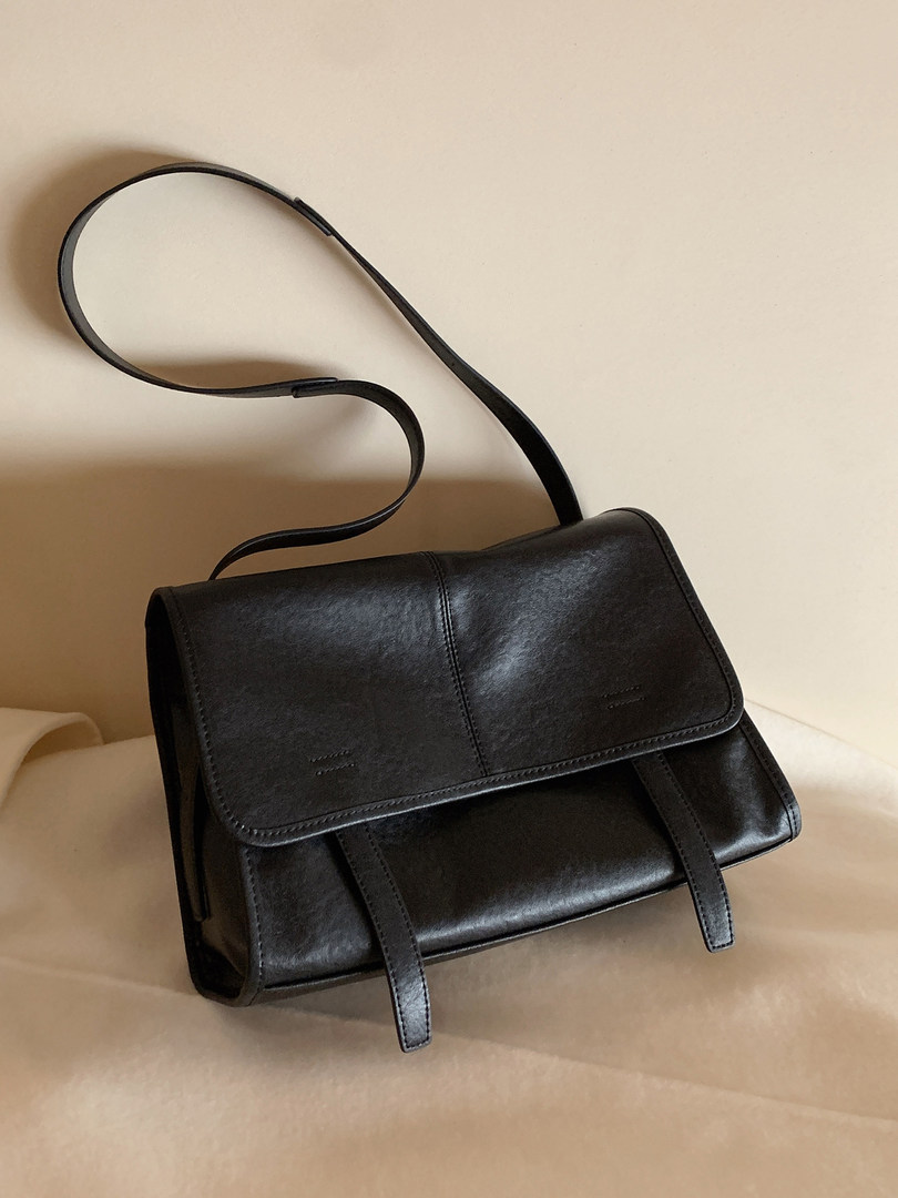 Black leather shoulder handbag on a plain background