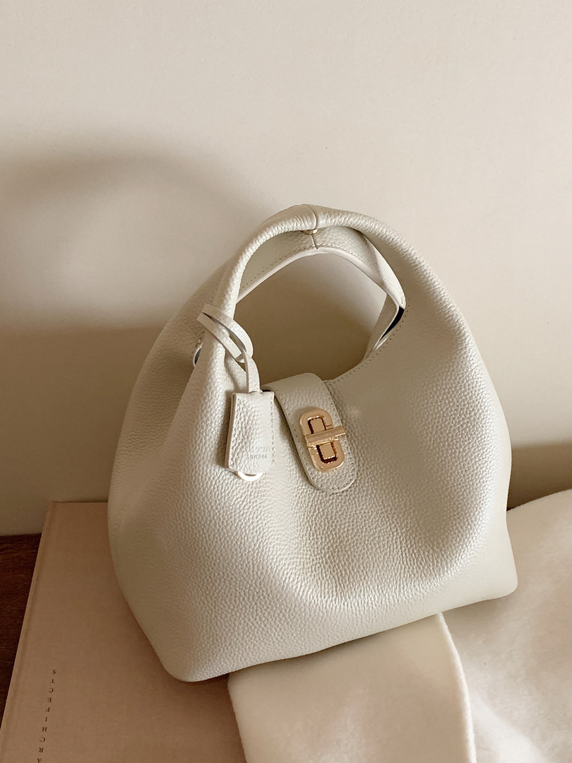 White textured leather handbag with gold-tone clasp on a neutral background
