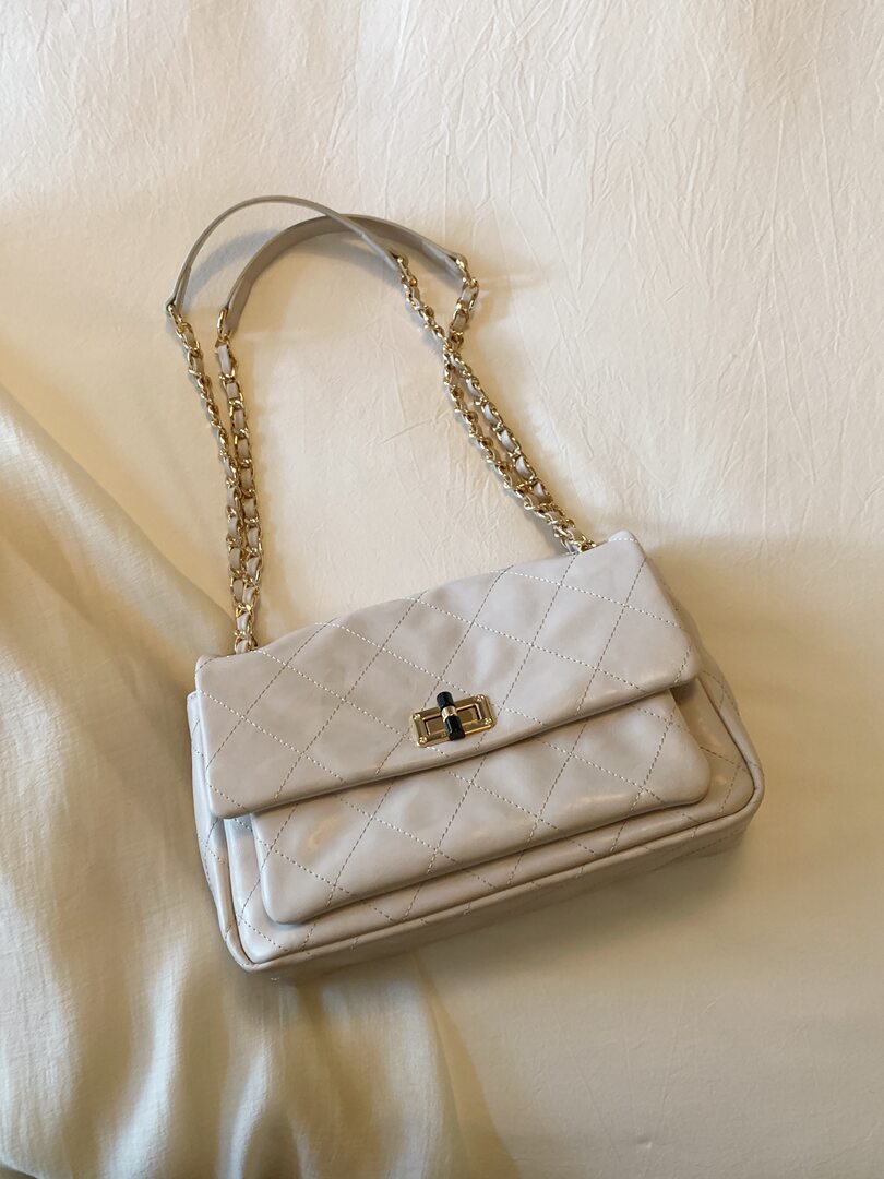 White quilted chain-strap handbag on a fabric background