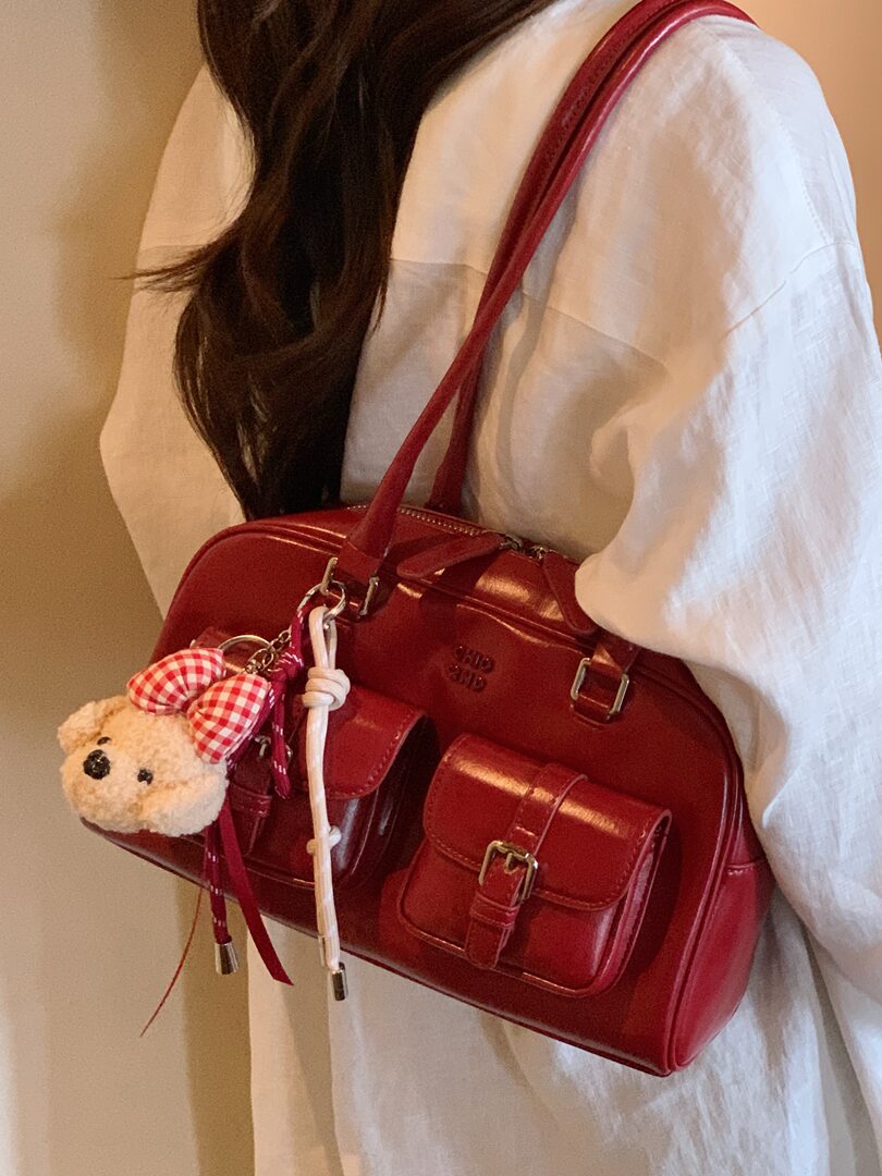 Red leather handbag worn over the shoulder with decorative charms