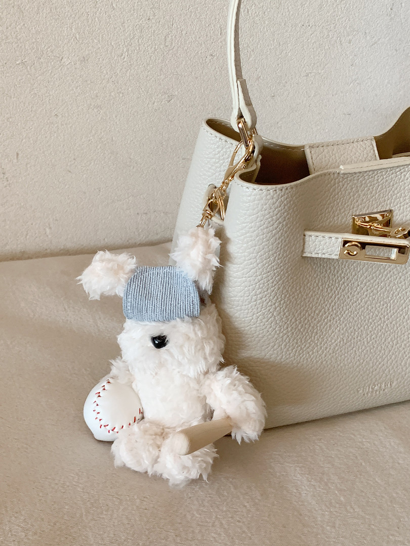 White textured leather handbag with gold hardware and a teddy bear charm