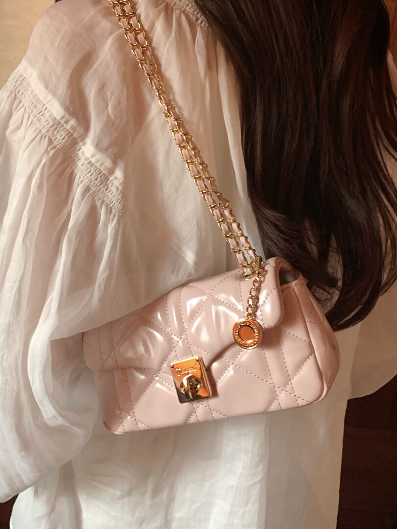 Pink quilted chain shoulder bag worn crossbody on a white blouse