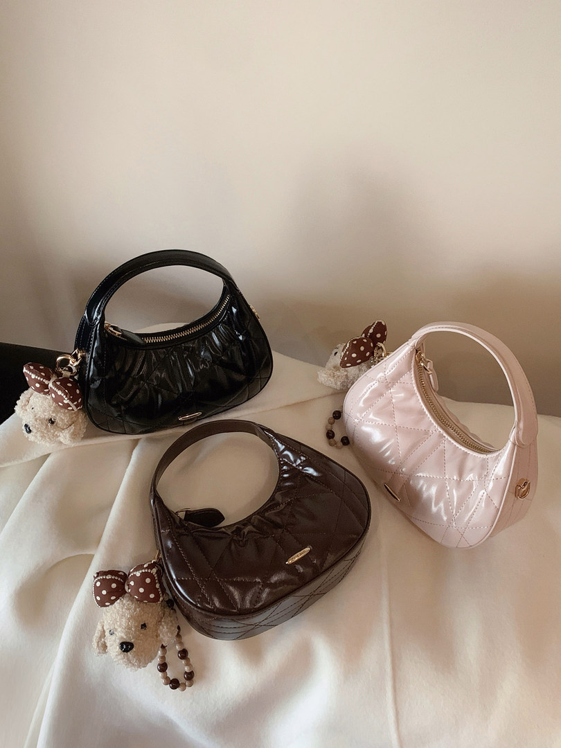 Three quilted handbag purses in black, brown, and pink with decorative bear charms