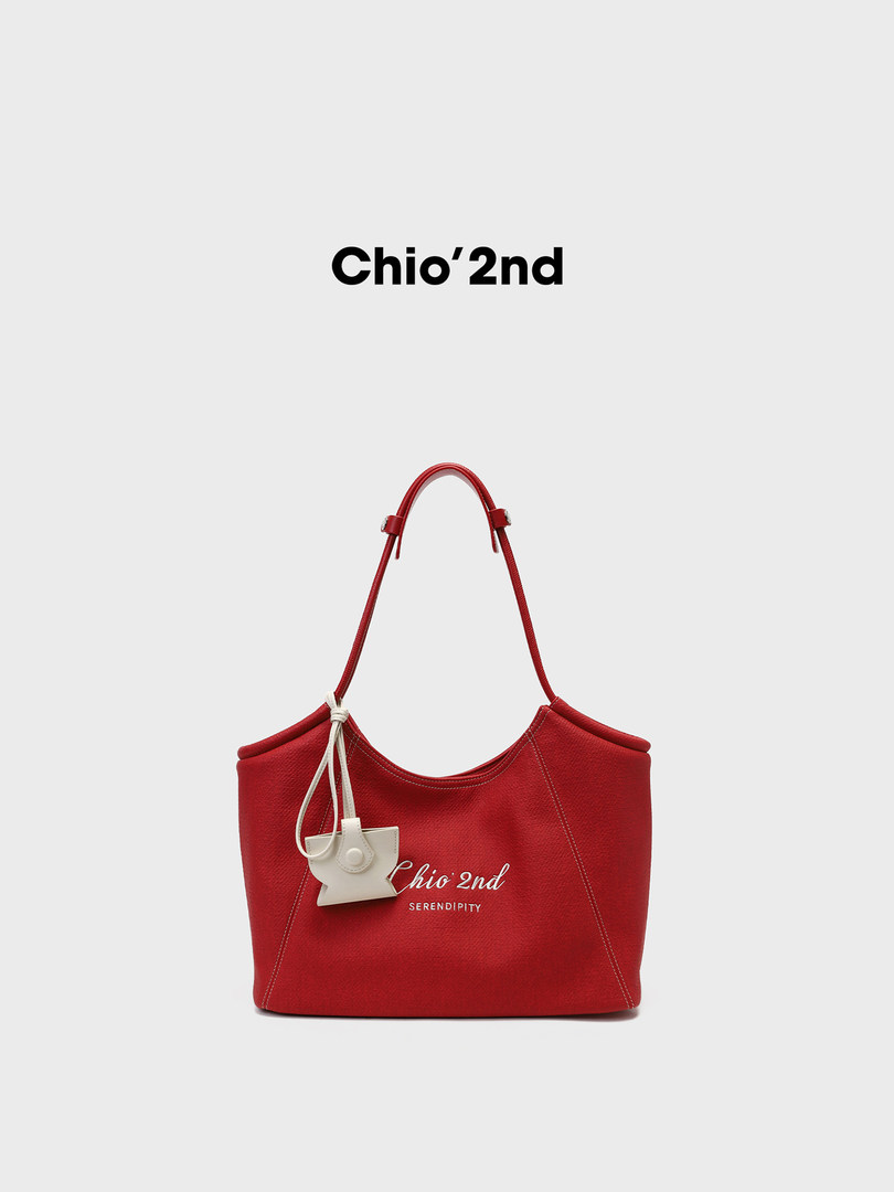 Red tote handbag with white charm detail on a plain background