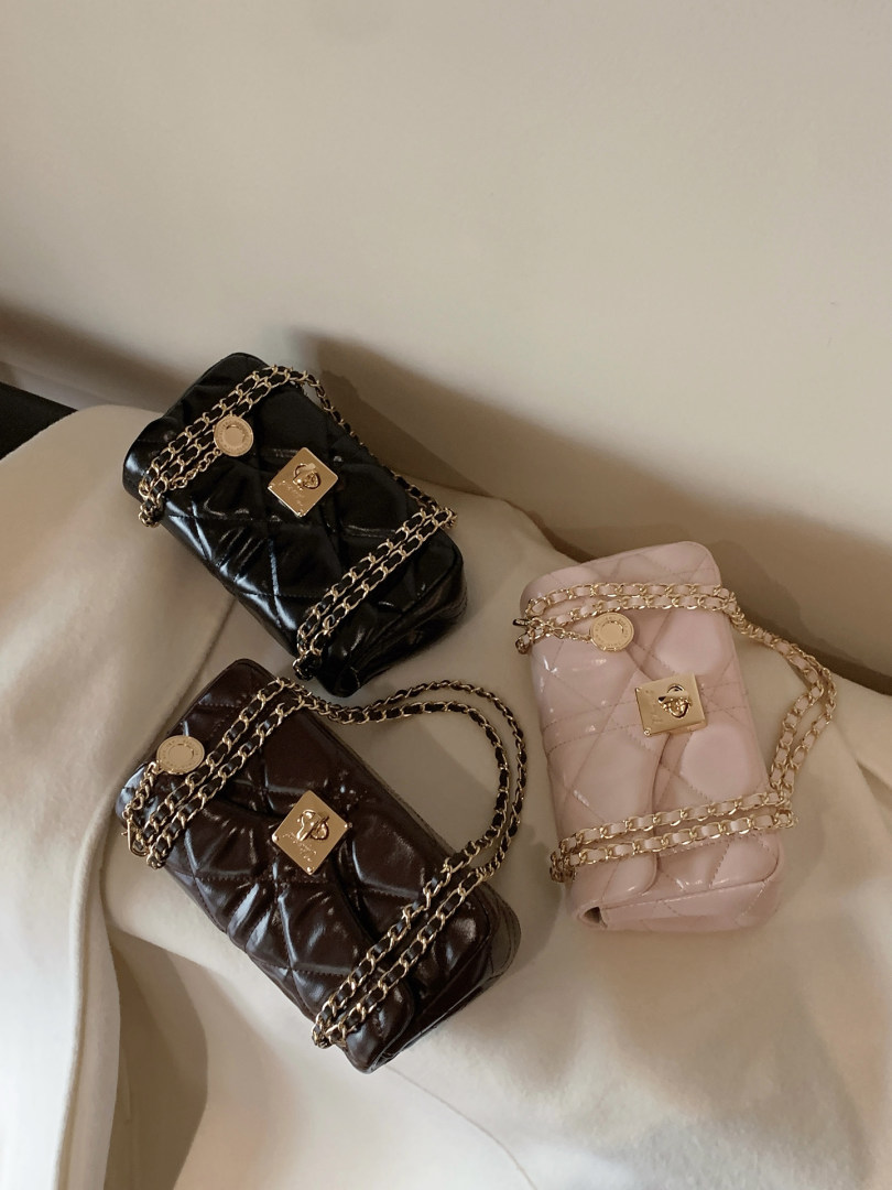 Three quilted chain-strap handbags in black, brown, and pink on a light couch