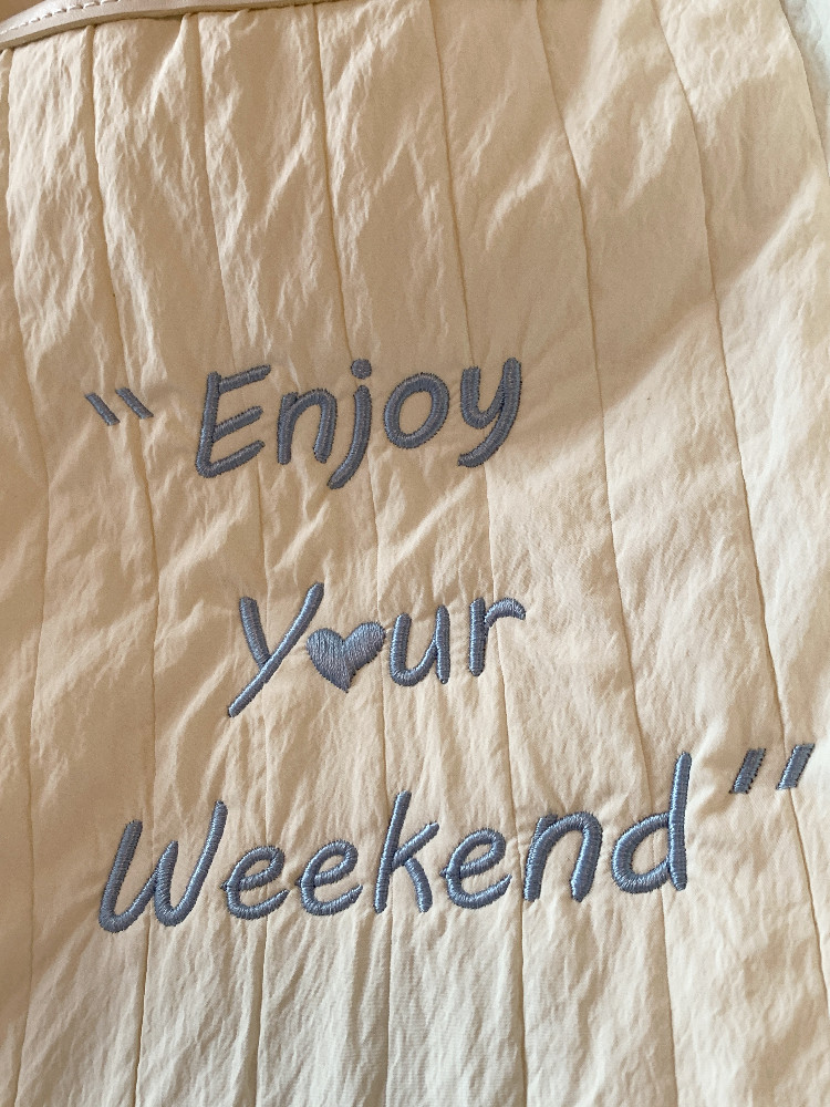 Beige quilted fabric with embroidered "Enjoy Your Weekend" text