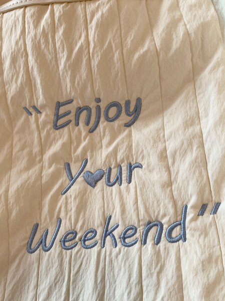 Beige quilted fabric with embroidered "Enjoy Your Weekend" text