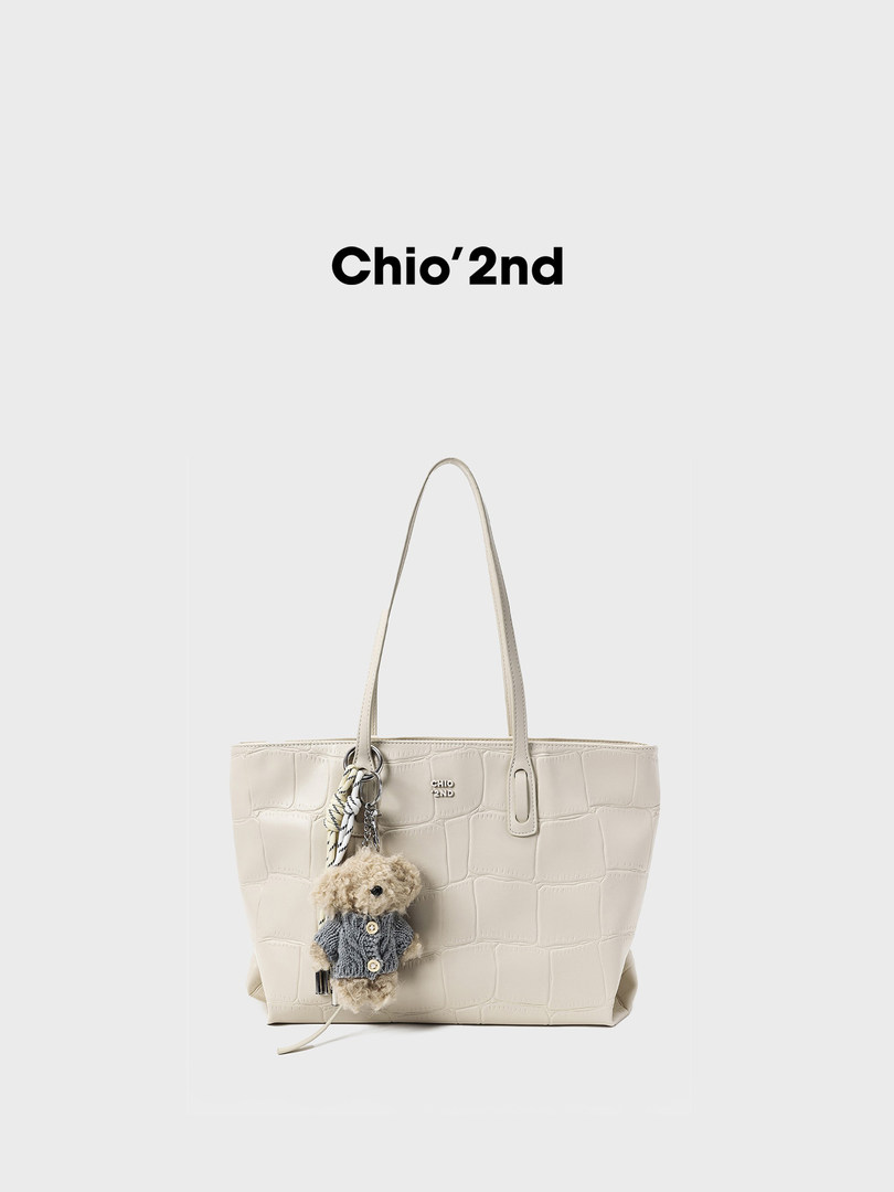 Cream textured tote bag with a teddy bear charm on a white background