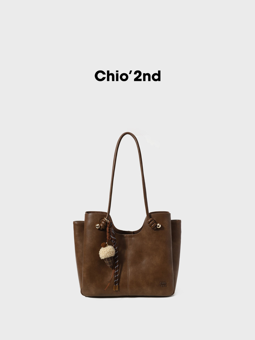 Brown leather tote bag with long shoulder strap and decorative charm