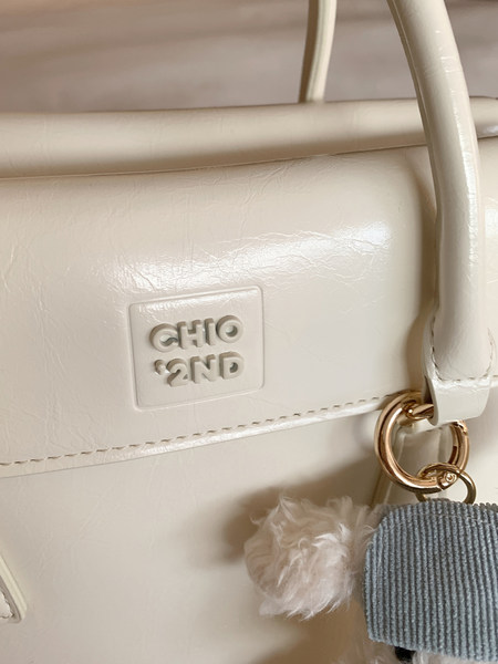 Cream-colored handbag with gold hardware and logo detail