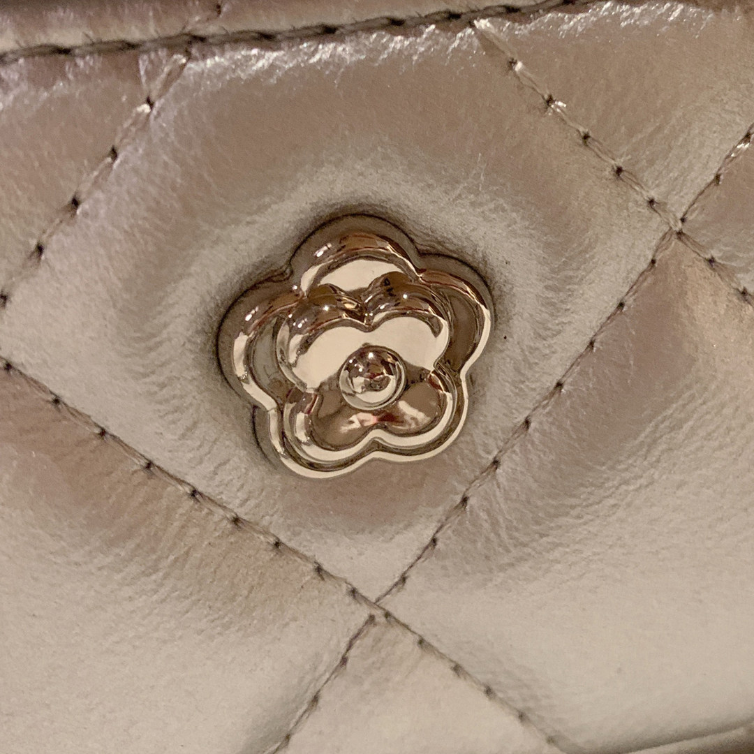 Close-up of a quilted beige leather bag with a gold flower-shaped clasp