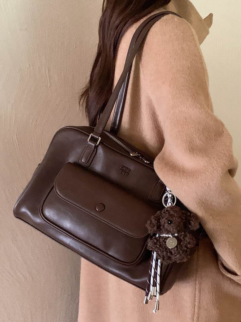 Brown leather handbag worn on the shoulder with a small charm keychain