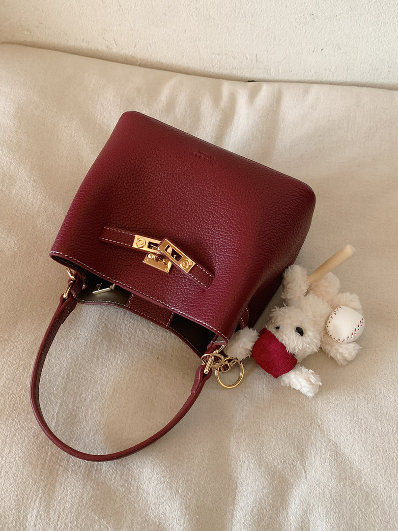 Burgundy leather handbag with gold-tone clasp and shoulder strap
