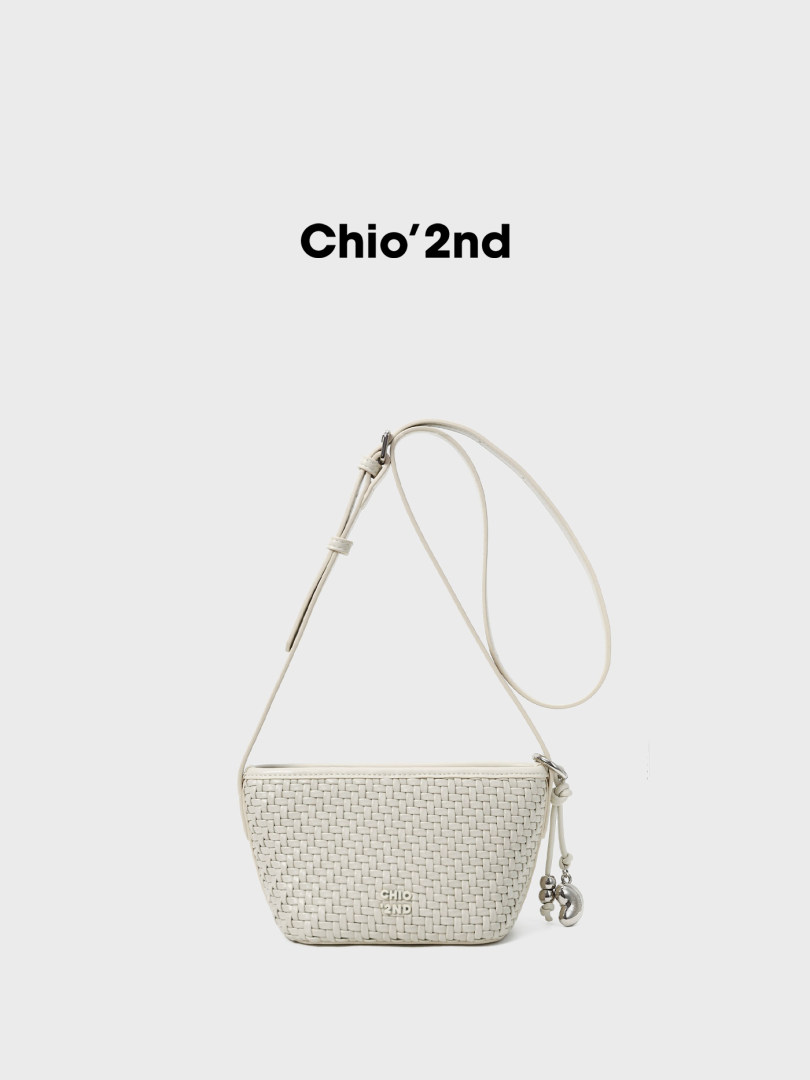 White woven crossbody bag with long strap on a plain background