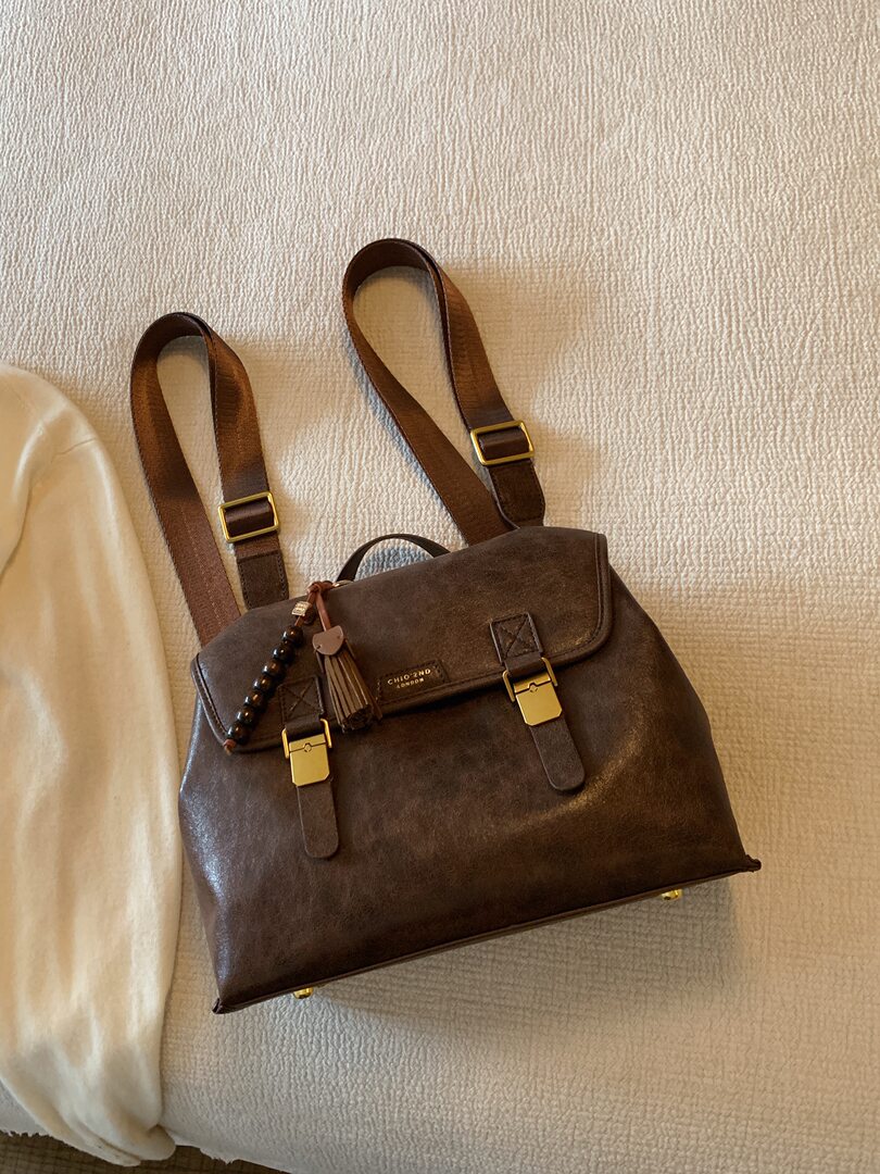 Brown leather backpack with gold buckles and long straps