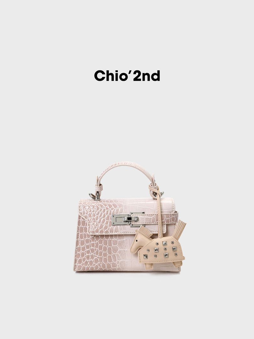 Light pink patterned handbag with decorative charm on a plain background