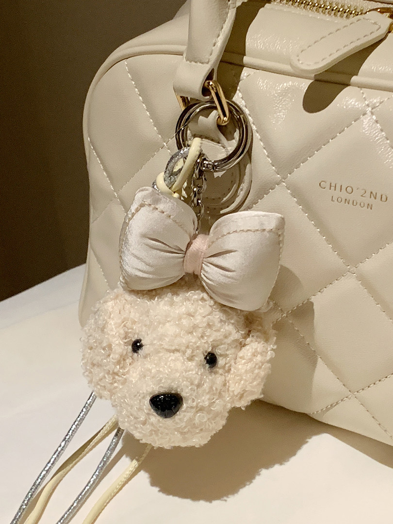 Cream quilted handbag with teddy bear charm and bow keychain