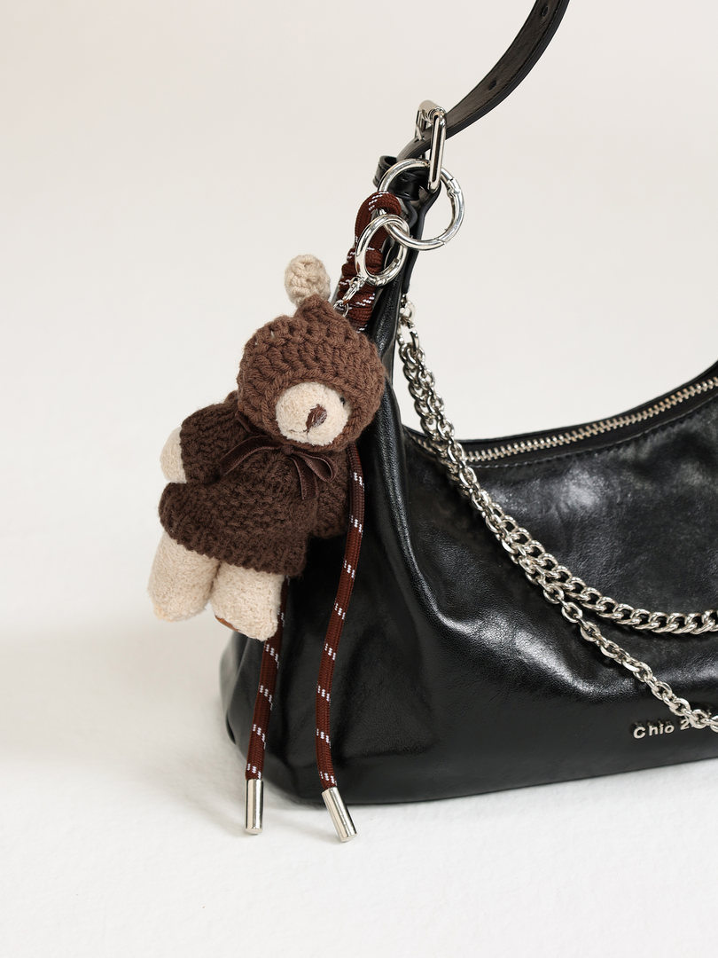 Black leather handbag with chain strap and teddy bear charm