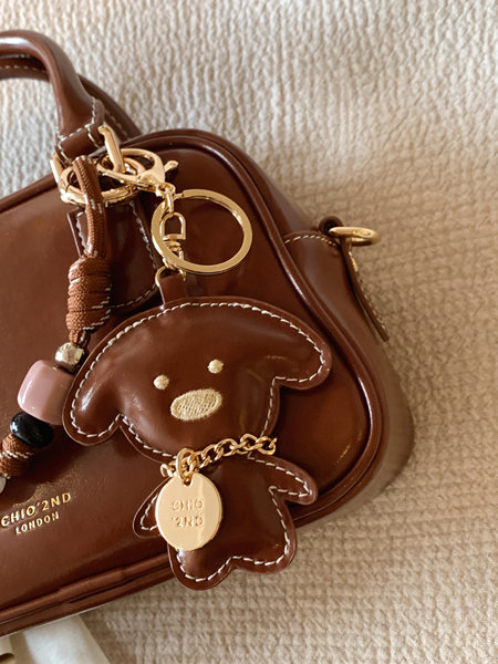 Brown leather handbag with teddy bear charm and gold hardware