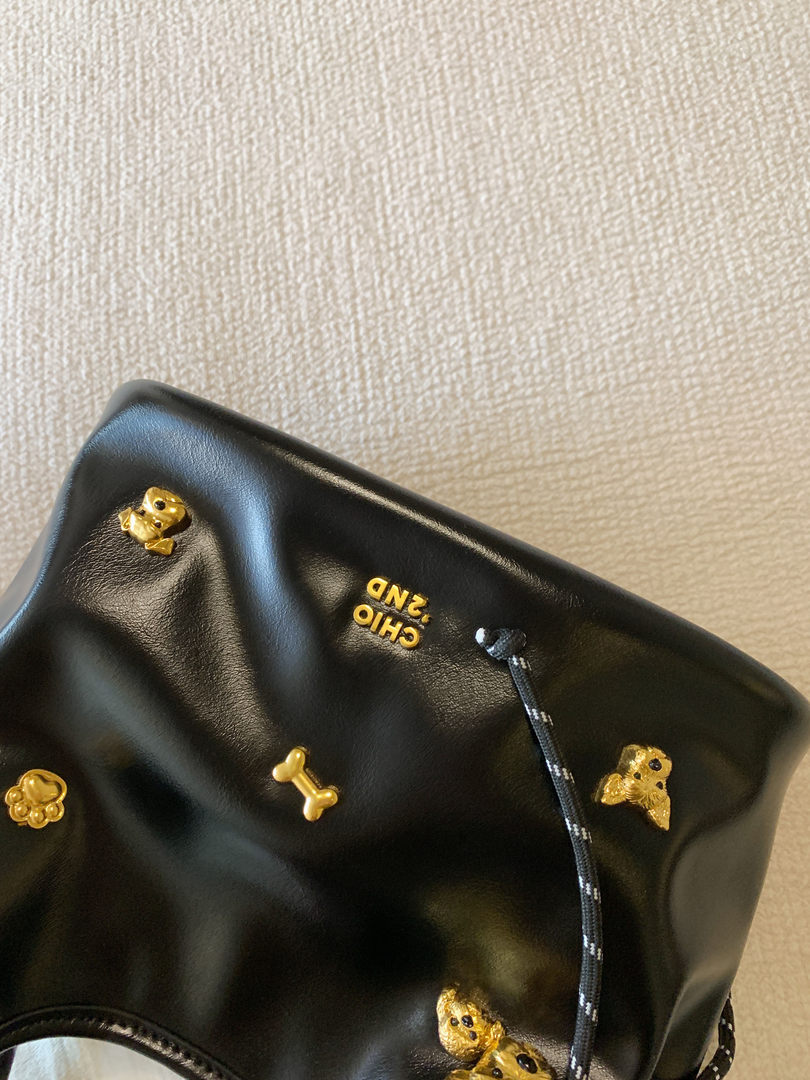 Black leather clutch or pouch with gold decorative charms and drawstring detail
