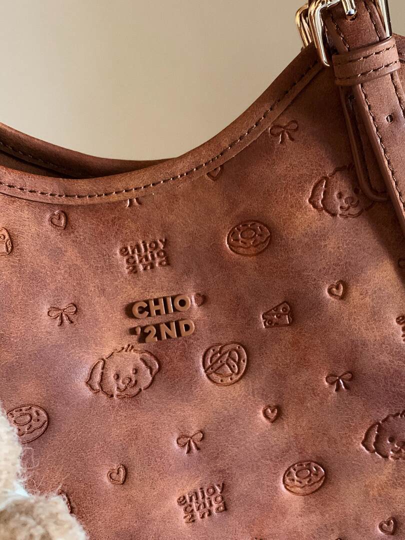 Brown leather handbag with embossed motifs and strap close-up