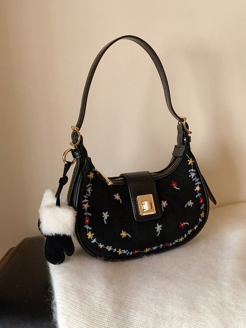 Black embroidered handbag with gold hardware and a fluffy charm