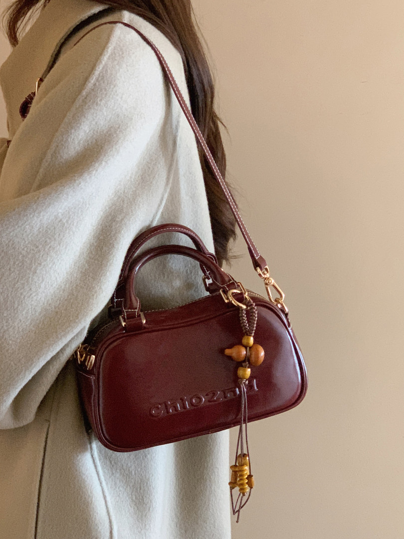 Burgundy leather handbag worn crossbody on a model