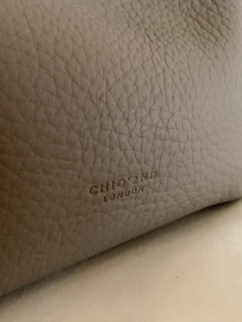 Close-up of beige pebbled leather with embossed CHLOE 2ND LONDON logo