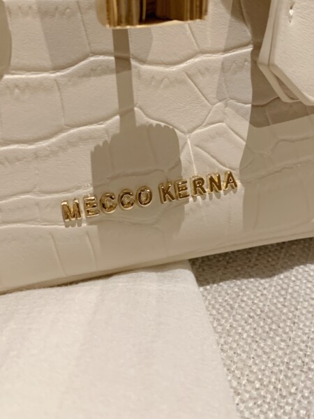 Close-up of a white quilted handbag with gold lettering