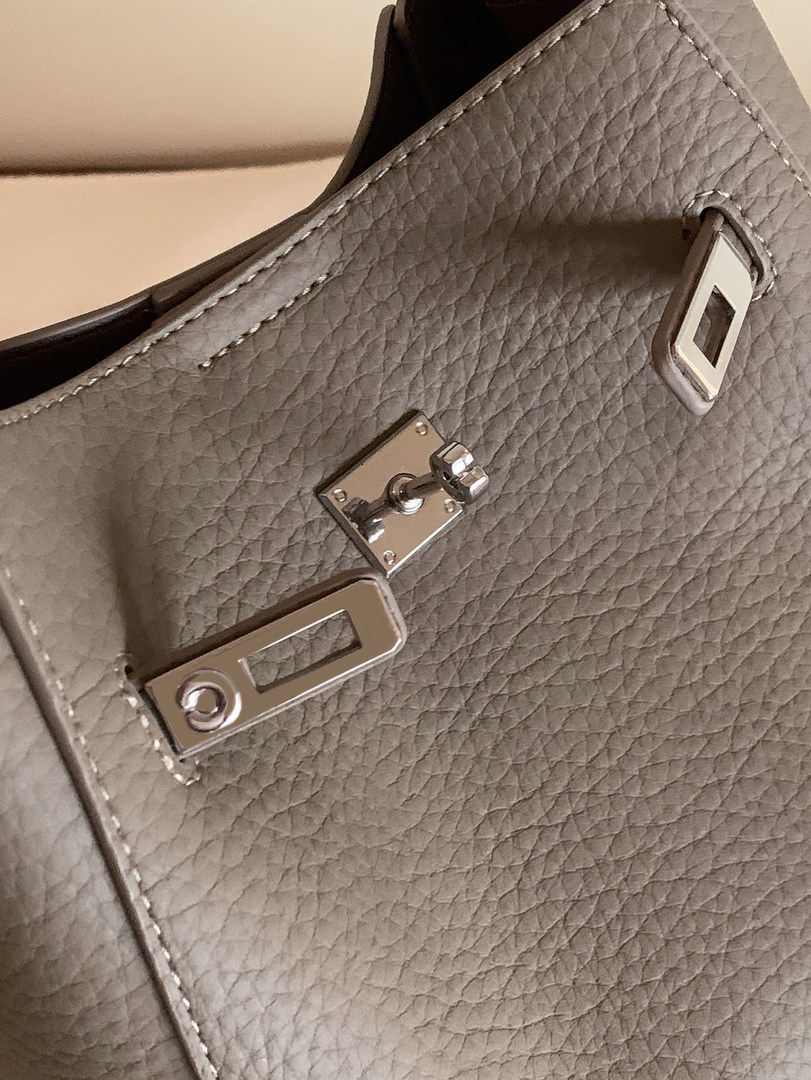 Close-up of a gray pebbled leather handbag with silver hardware