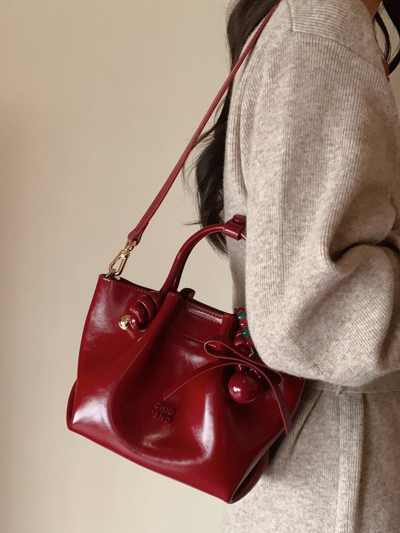 Red glossy handbag worn crossbody on a model