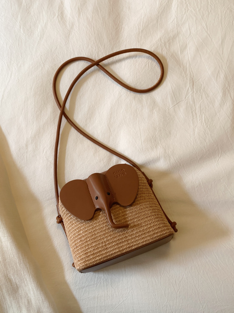 Brown woven elephant-shaped crossbody bag with a long strap