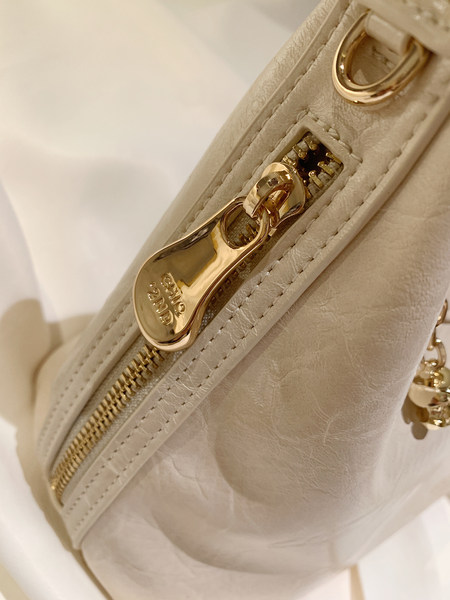 Close-up of a cream leather handbag with gold zipper hardware