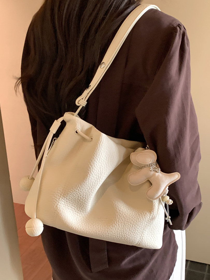 White textured shoulder bag worn over a dark outfit
