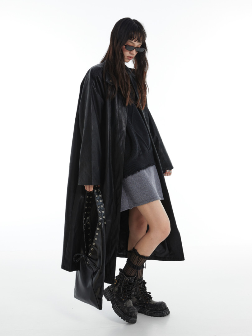 Black long coat worn by a model with boots and sunglasses