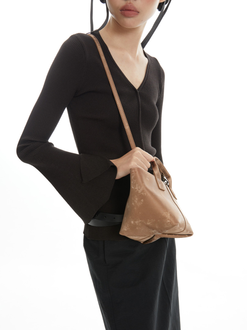 Model wearing a black long-sleeve top with a tan shoulder bag