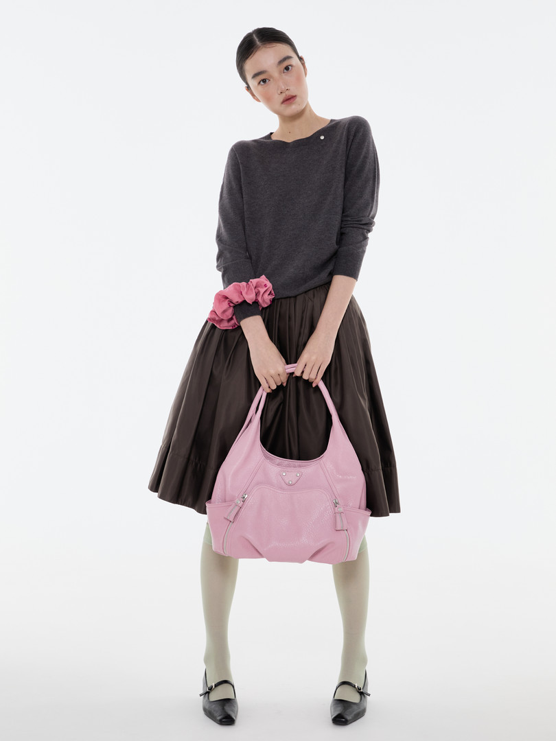 Model wearing a dark outfit and holding a pink handbag