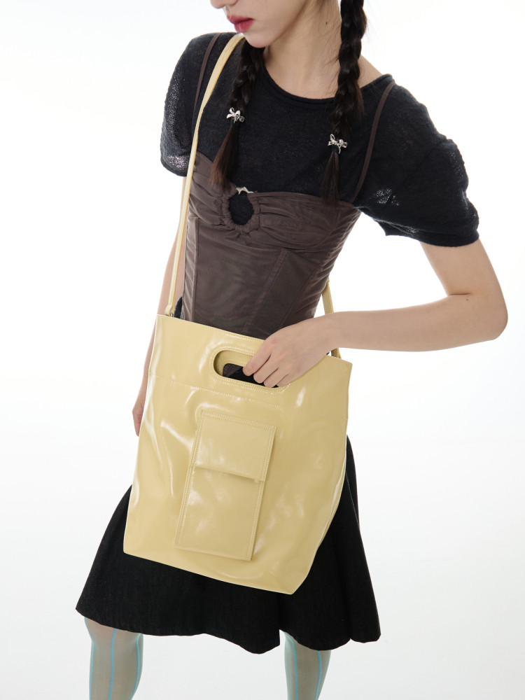 Yellow glossy shoulder tote bag worn by a model