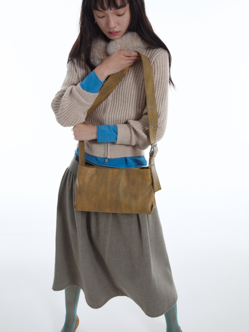 Brown crossbody shoulder bag worn by a model with a layered outfit