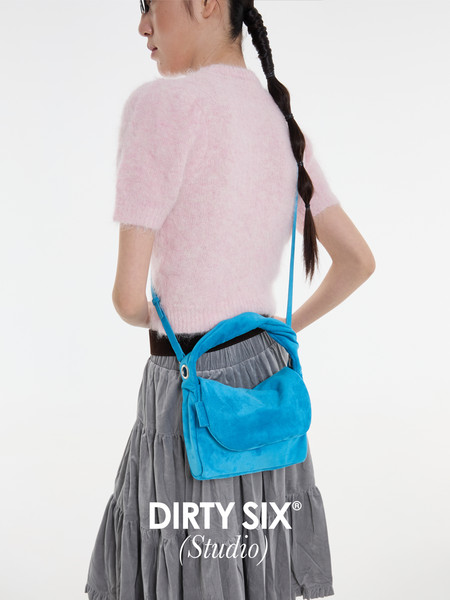 Model wearing a bright blue shoulder bag with a pink fuzzy top and gray skirt