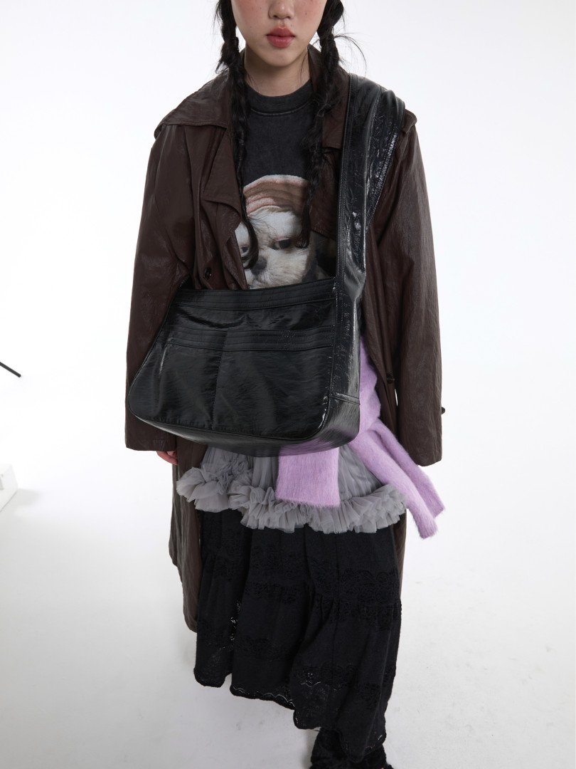 Fashion model wearing a layered dark outfit with a large black shoulder bag