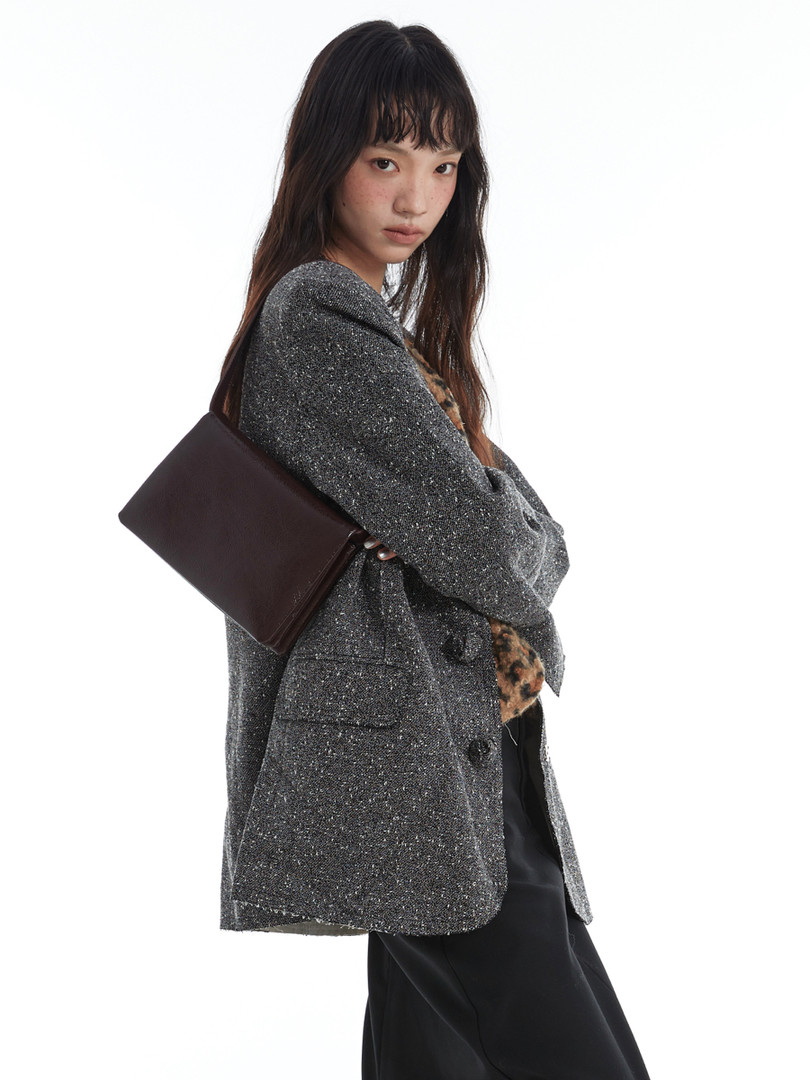 Model wearing a sparkly gray blazer with a dark shoulder bag