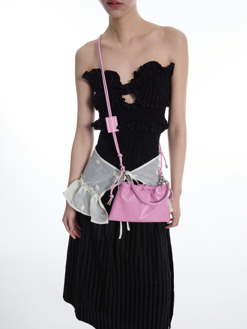 Model wearing a black strapless dress with a pink crossbody bag